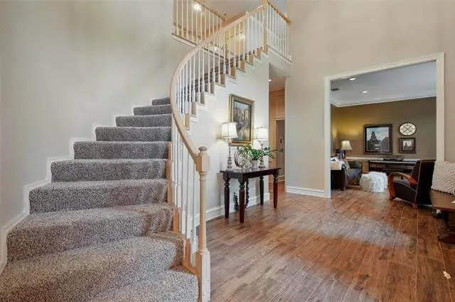 Modern indoor design of an open-concept living room in Plano, TX with light oak floors, neutral furniture, and floor-to-ceiling windows after