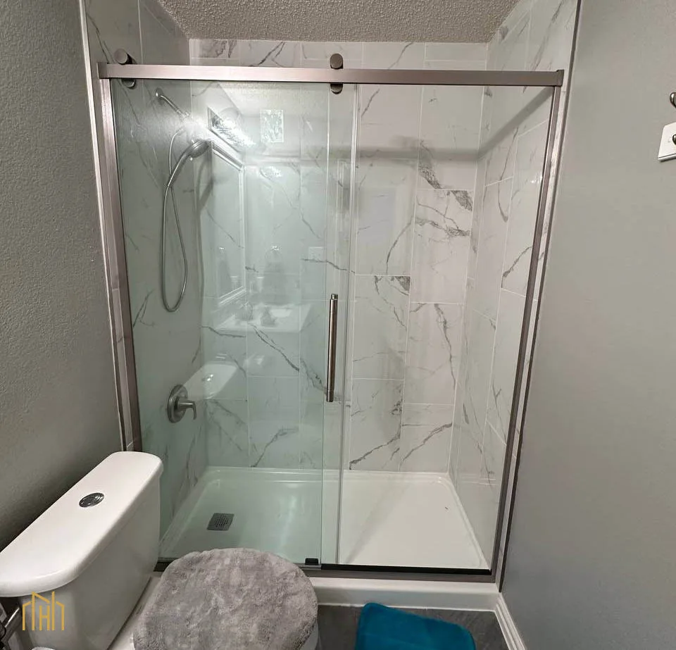 Compact walk-in shower with frameless glass door and built-in recessed niche for storage in a townhome bathroom.