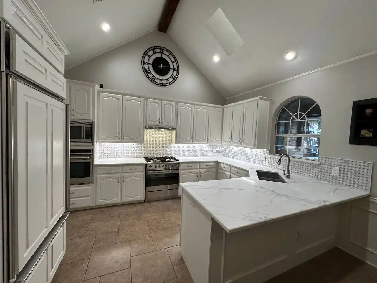 Updated kitchen after renovation featuring fresh countertops, new backsplash tiles, and white cabinetry